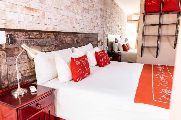 Slaapkamer met oranje kussentjes in het Londiningi Guesthouse