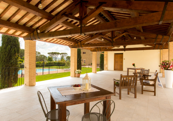 Overdekt terras bij een agriturismo met op de achtergrond het zwembad